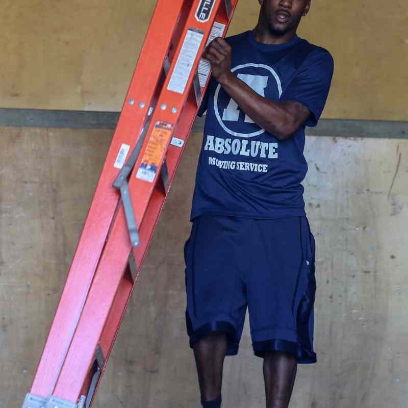 A smiling Absolute crew member in uniform carrying a ladder